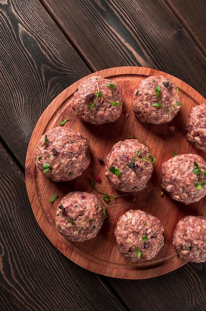 Albóndigas crudas con micro vegetación en una tabla de cortar casera rústica sin gente