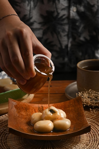 Albóndigas dulces servidas en un plato de madera con sopa de jengibre dulce.