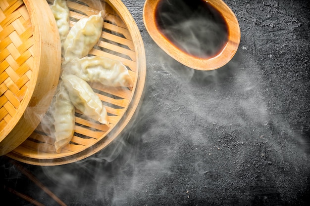 Foto albóndigas gedza tradicionales chinas calientes en vapor de bambú con salsa de soja