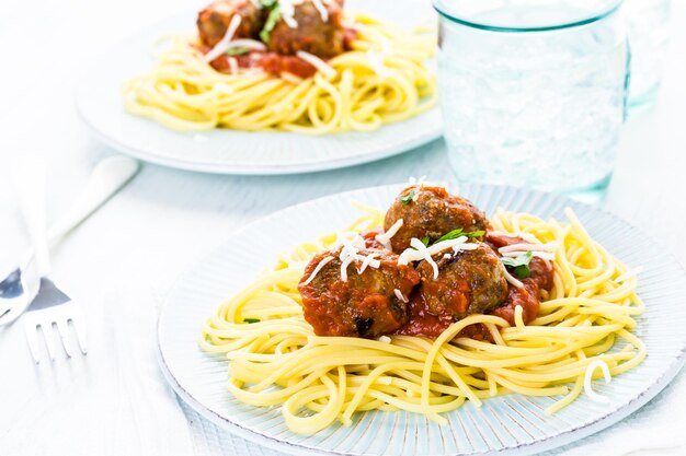 Albóndigas italianas caseras adornadas con cilantro y queso parmesano sobre espaguetis para la cena.