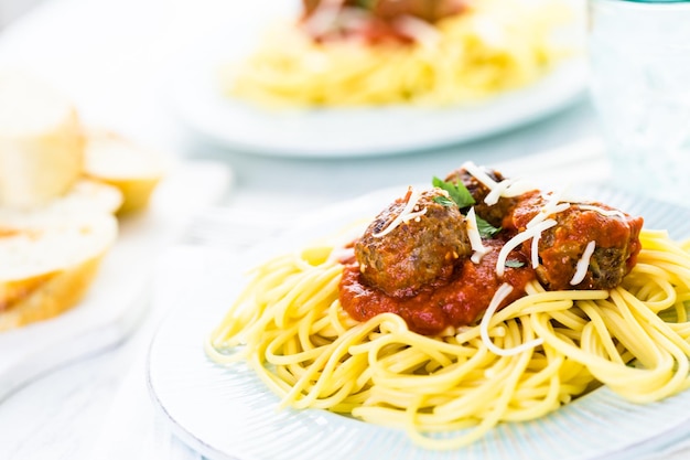 Albóndigas italianas caseras adornadas con cilantro y queso parmesano sobre espaguetis para la cena.