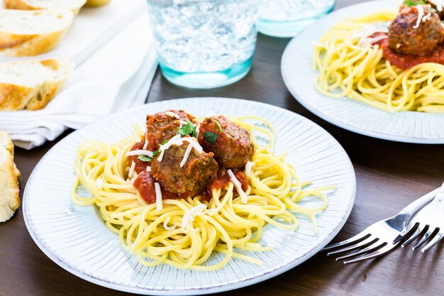 Albóndigas italianas caseras adornadas con cilantro y queso parmesano sobre espaguetis para la cena.