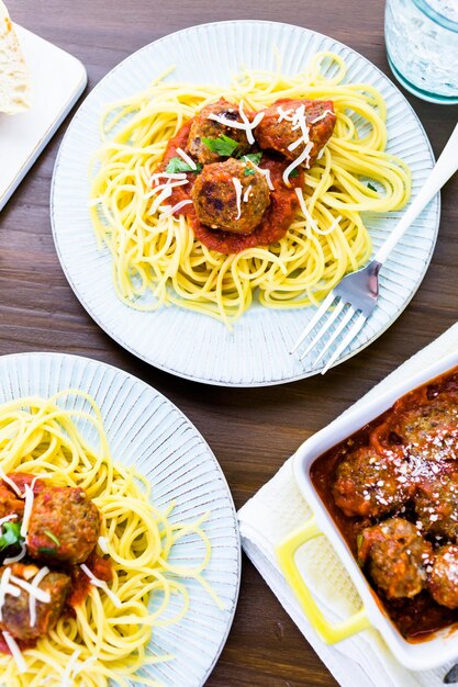 Albóndigas italianas caseras adornadas con cilantro y queso parmesano sobre espaguetis para la cena.