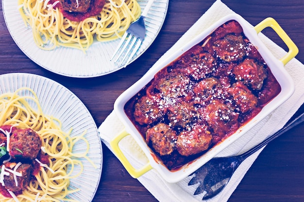 Albóndigas italianas caseras adornadas con cilantro y queso parmesano sobre espaguetis para la cena.