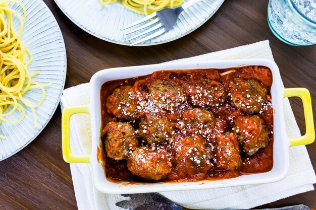 Albóndigas italianas caseras adornadas con cilantro y queso parmesano sobre espaguetis para la cena.