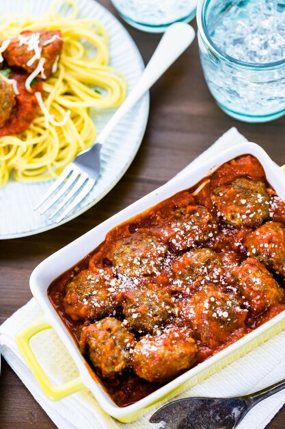 Albóndigas italianas caseras adornadas con cilantro y queso parmesano sobre espaguetis para la cena.