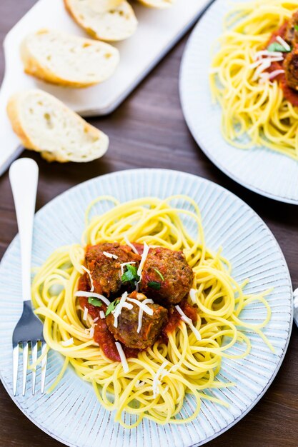 Albóndigas italianas caseras adornadas con cilantro y queso parmesano sobre espaguetis para la cena.