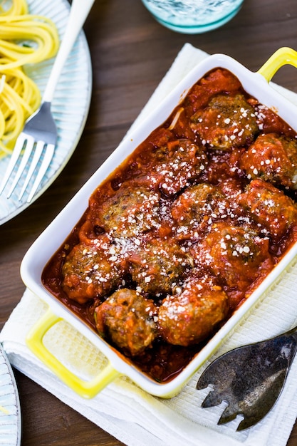 Albóndigas italianas caseras adornadas con cilantro y queso parmesano sobre espaguetis para la cena.