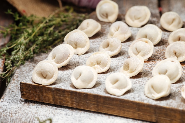 Albóndigas pelmeni semiacabadas sobre tabla de madera