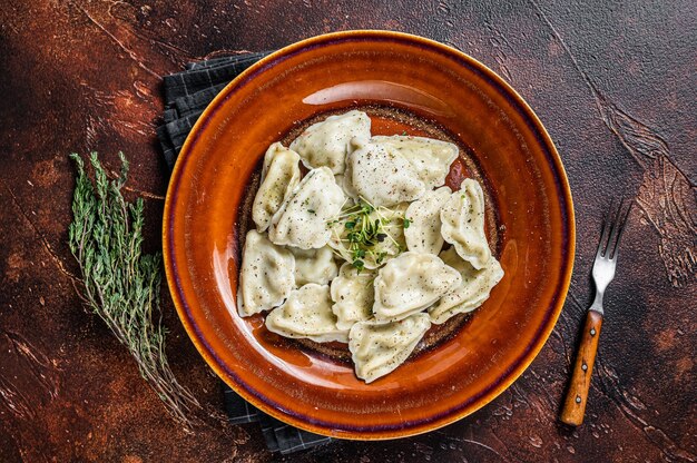 Albóndigas Pierogi polacas con patatas en un plato con hierbas y mantequilla. Vista superior.