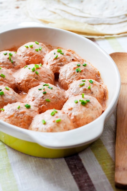 Albóndigas de pollo caseras al horno en salsa cremosa de tomate en una fuente para hornear de cerámica