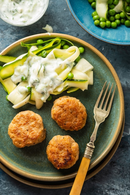 Albóndigas de pollo con ensalada de calabacín y guisantes, con salsa de yogur y ajo.