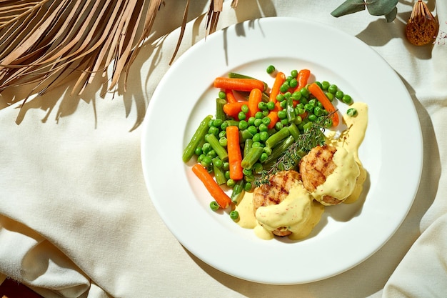 Albóndigas de pollo con verduras al vapor en un plato Tough light Mantel blanco