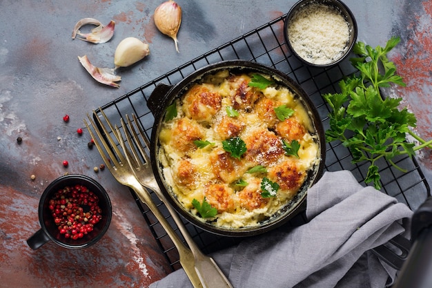 Albóndigas con queso y salsa de crema en sartén de hierro fundido sobre superficie vintage gris