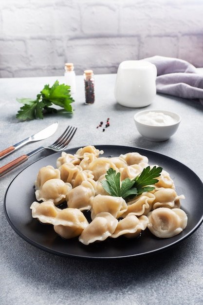 Albóndigas de ravioli de pelmeni tradicionales rellenas de carne en un plato de cocina rusa Espacio de copia de fondo de hormigón ligero