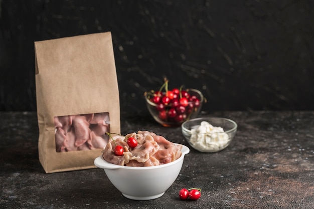 Albóndigas rojas con cerezas en un bol y embalaje de papel ecológico para entrega con salsa blanca