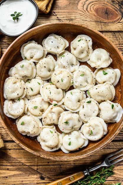 Albóndigas rusas caseras Pelmeni con carne de res y cerdo en un cuenco de madera.