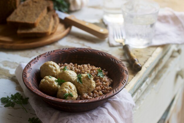 Albóndigas en salsa de crema agria, servidas con gachas de trigo sarraceno, pan y ajo. estilo rústico