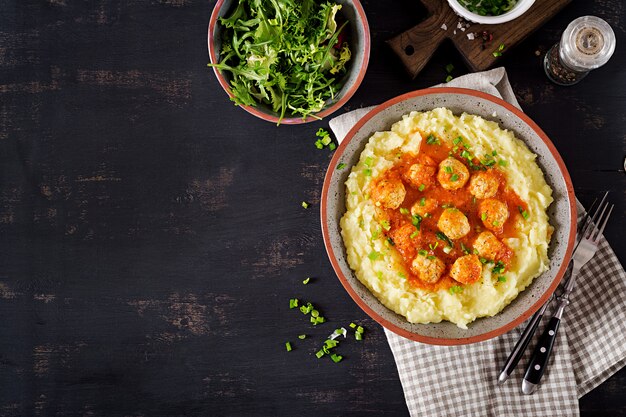 Albóndigas en salsa de tomate con puré de papas en un tazón. Vista superior