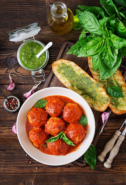 Foto albóndigas en salsa de tomate y tostadas con pesto de albahaca.