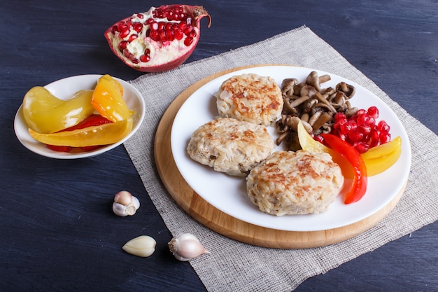 Albóndigas con setas de arroz, pimientos dulces y semillas de granada sobre madera negra.