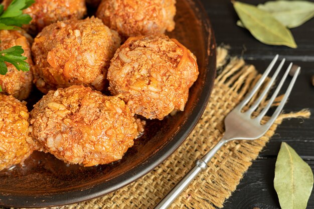 Foto albóndigas sobre un fondo de madera con hojas de salvia y perejil. almuerzo casero.