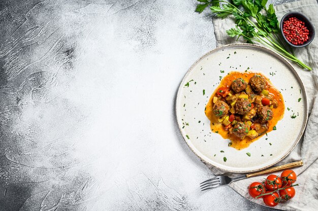 Albóndigas de ternera con salsa de tomate y verduras en una sartén. Fondo gris Vista superior. Espacio para texto