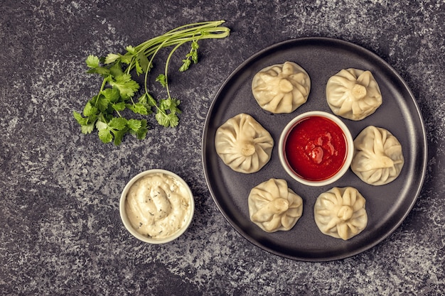 Albóndigas tradicionales al vapor Khinkali con tomate y salsa tártara