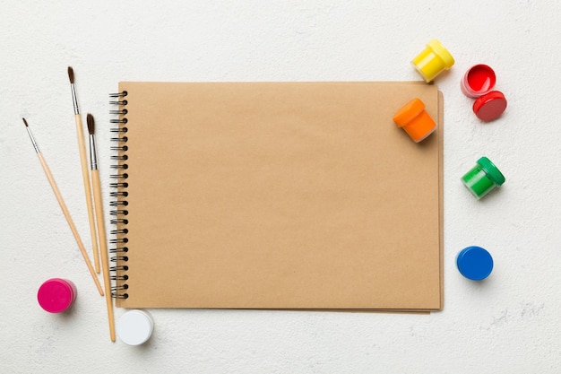Albumseiten und Farben Bleistiftpinsel auf farbigem Hintergrund Draufsicht mit leerem Raum Arbeitsplatz für Kreativität Konzeptzeichnung für den Heimunterricht