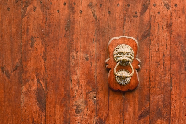 Alça de latão em forma de cabeça de leão com um anel em seus dentes no antigo portão de madeira