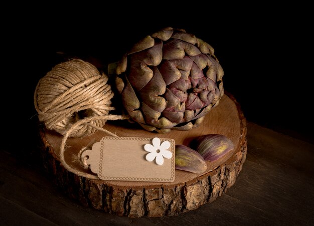 Foto alcachofa con cordel enrollado en tronco de madera.