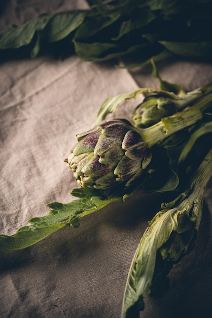 Alcachofa fresca con hojas sobre fondo textil rústico