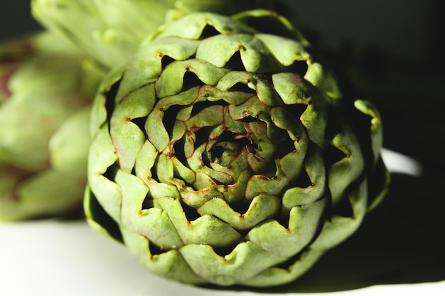 Alcachofra fresca em um fundo branco de madeira com sombra linda luz do dia, close-up. Uma flor de alcachofra orgânica crua