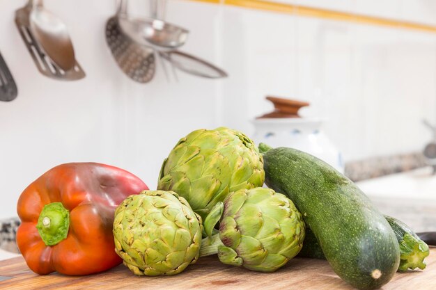 Alcachofras e abobrinhas de pimenta crua na mesa da cozinha alimentos naturais