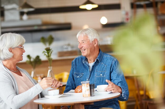 Alcançando uma xícara de chá Foto de um casal sênior feliz relaxando com uma xícara de café em uma cafeteria