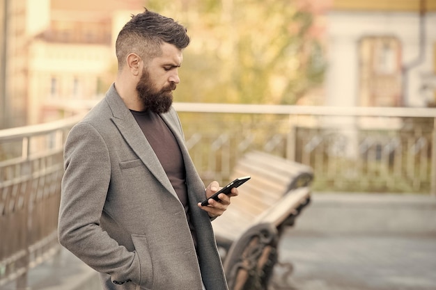 Alcance pessoas em movimento com sms marketing Homem barbudo lê sms urbano ao ar livre Mensagens de texto Dispositivo móvel Nova tecnologia Vida moderna Comunicação empresarial