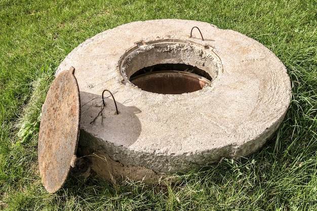 Alcantarillado de hormigón con tapa abierta en la naturaleza.