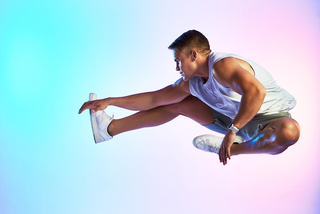 Alcanzando nuevas alturas Foto de estudio de un apuesto joven atleta saltando contra un fondo multicolor