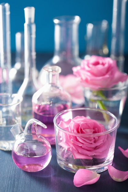 Alchemie und Aromatherapie mit Rosenblüten und chemischen Flaschen