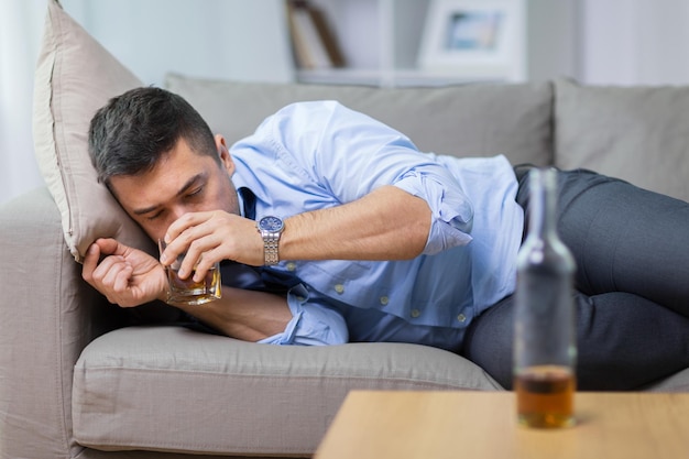 alcohólico acostado en el sofá y bebiendo whisky