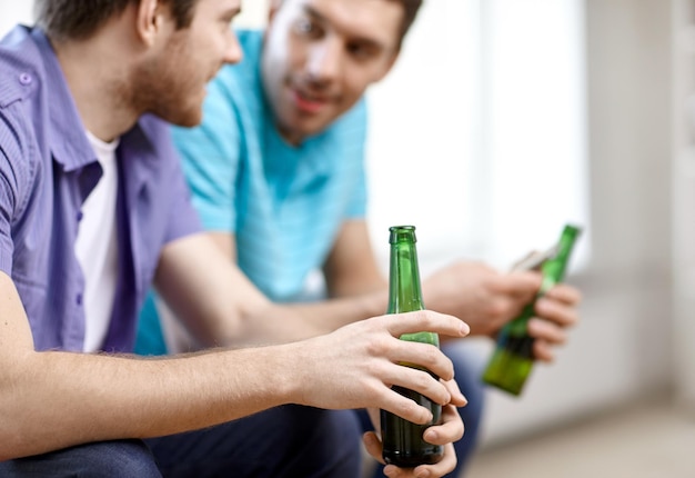 álcool, comunicação, amizade, pessoas e conceito de lazer - close-up de amigos do sexo masculino bebendo cerveja em casa