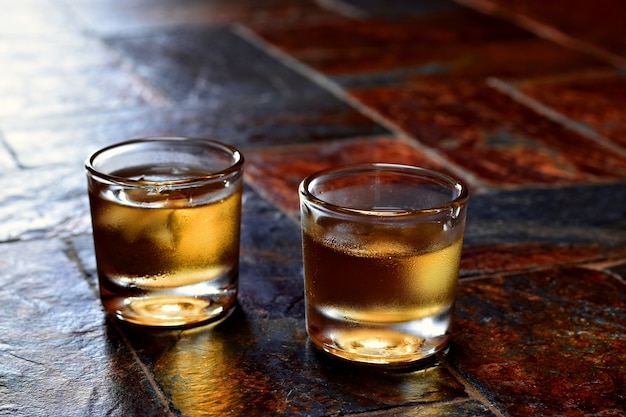 Álcool, gosto e bebida concep-dois vidros do uísque em um fundo de pedra velho.