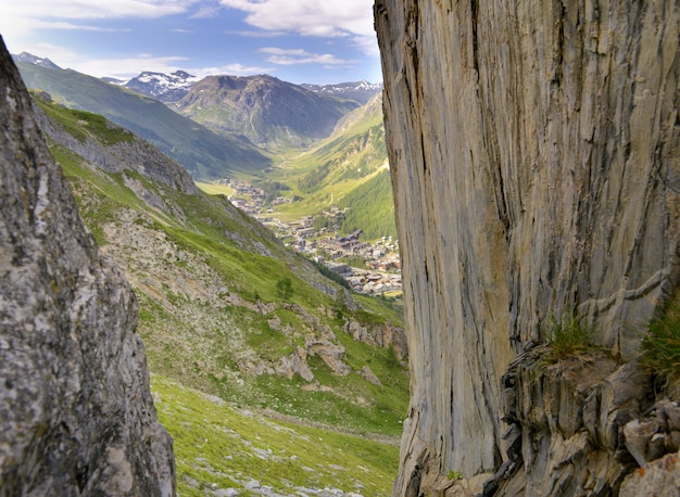 Aldeia alpina no vale europeu por trás da parede rochosa