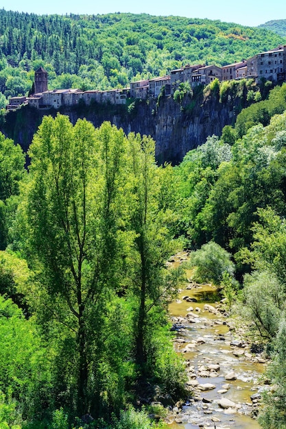 Aldeia medieval pendurada na ravina com o riacho correndo sob as rochas Castellfollit de la Roca Girona