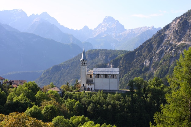 Aldeia na montanha com a igreja nos Alpes