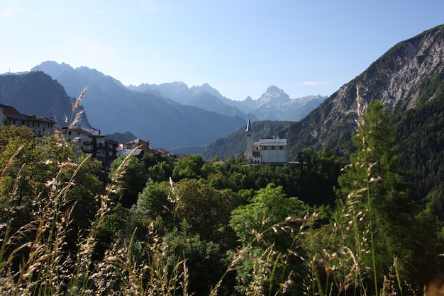 Aldeia na montanha com a igreja nos Alpes