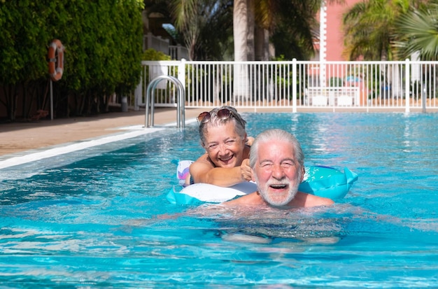 Alegre 70s adulto maduro activo feliz senior pareja de abuelos divirtiéndose en la piscina