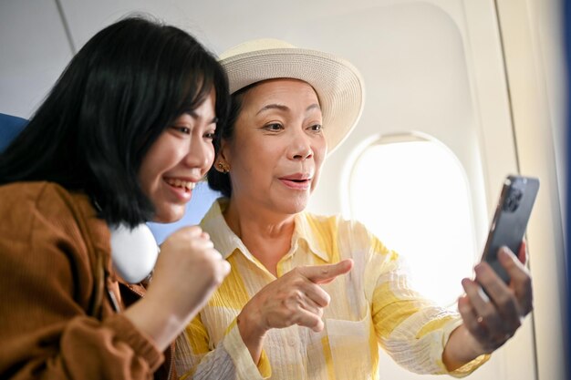 Una alegre abuela asiática disfruta grabando videos con su nieta durante el vuelo