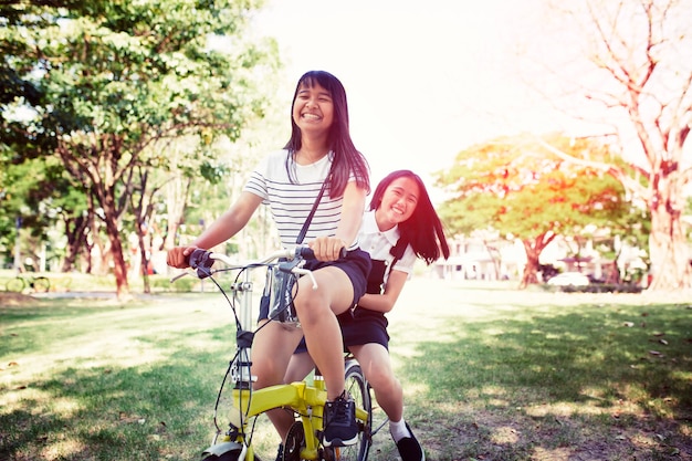 Alegre adolescente asiático montando bicicleta en el parque pulbic