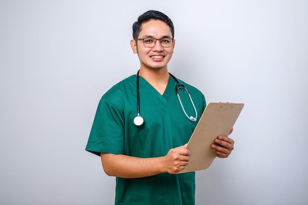 Alegre y amable médico asiático masculino con portapapeles durante el chequeo diario